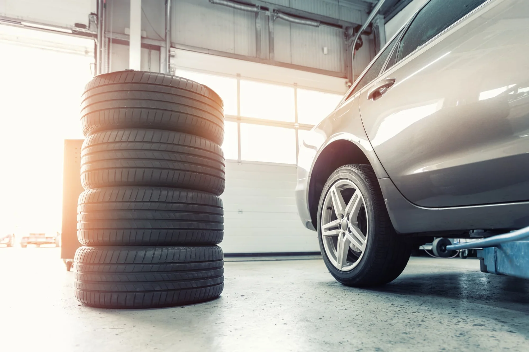 Stack of tyres beside a car inside a garage